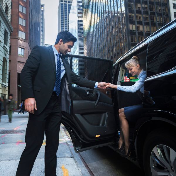 chauffeur helping client out of car